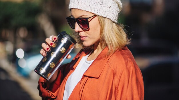 Mujer con estilo bebiendo bebidas calientes en la calle