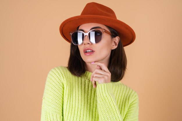 Mujer con estilo de moda en un suéter y un sombrero y gafas de sol con gafas marrones posando