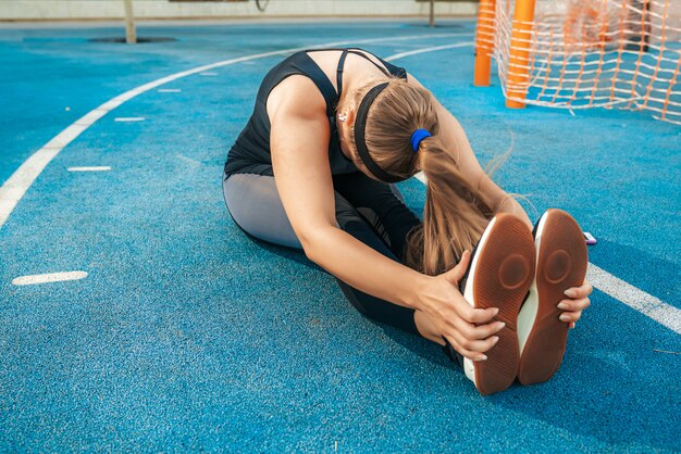 Mujer estira los músculos en el gimnasio al aire libre