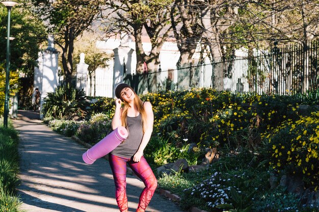 Mujer con estiramiento estera posando en el parque