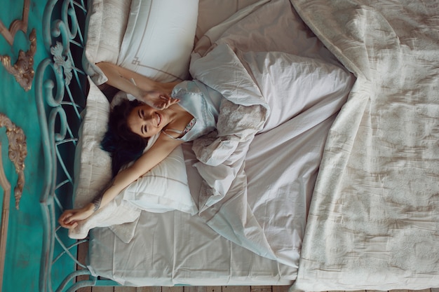 Mujer estirando en la cama después de despertarse