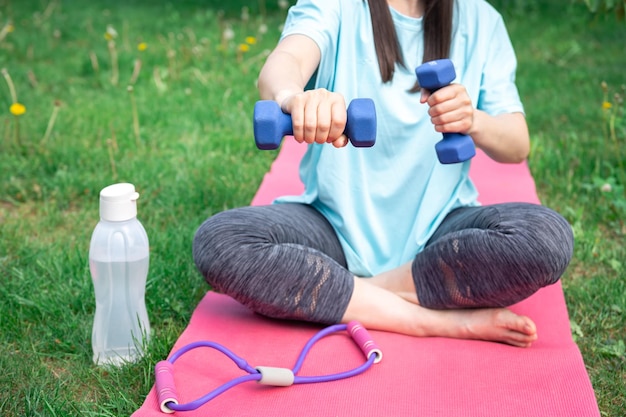 Foto gratuita mujer estirando con pesas haciendo ejercicios de fitness en green park