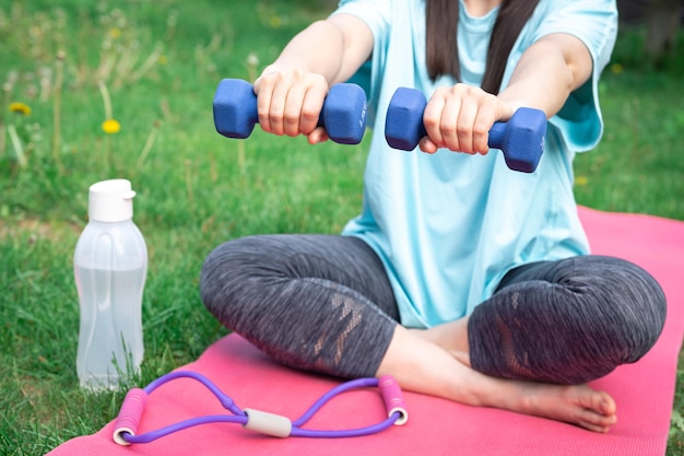 Foto gratuita mujer estirando con pesas haciendo ejercicios de fitness en green park