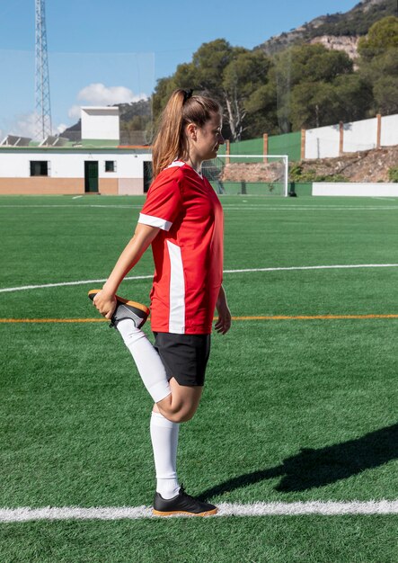 Mujer estirando la pierna en el campo de fútbol