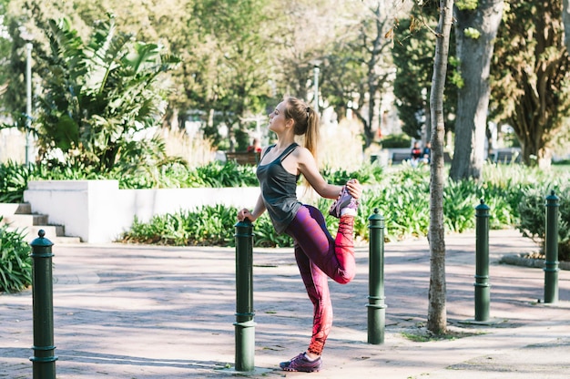 Mujer estirando la pierna en el parque