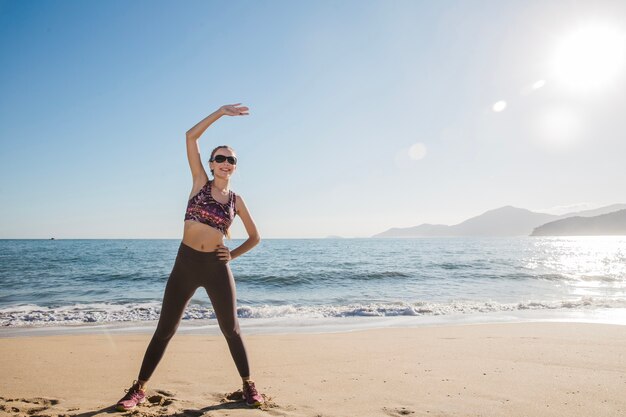 Mujer estirando en la playa