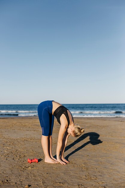 Mujer estirando en la playa