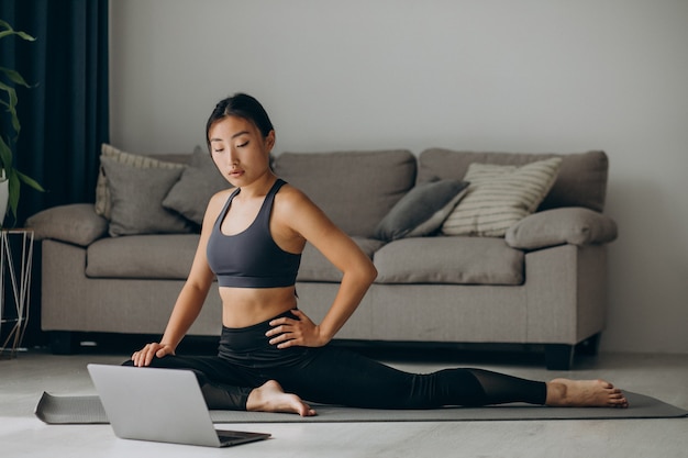 Mujer estirando sobre estera de yoga en casa