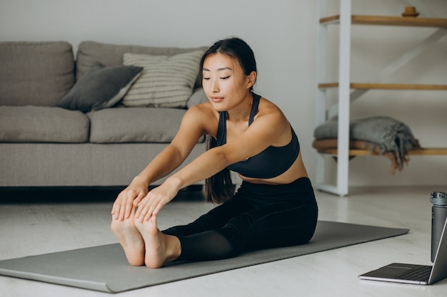 Mujer estirando sobre estera de yoga en casa