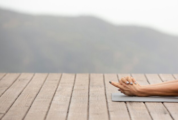 Mujer estirando sus brazos mientras hace yoga al aire libre con espacio de copia