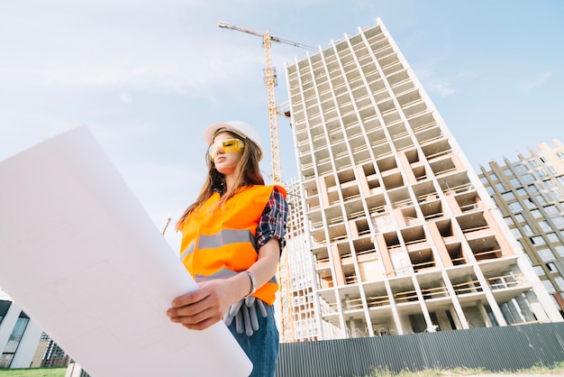 Mujer estudiando borrador en el sitio de construcción