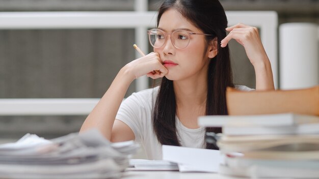 Mujer estudiante asiática lee libros en la biblioteca de la Universidad