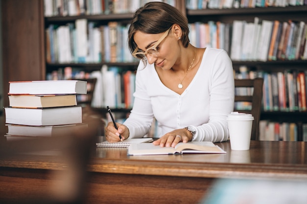 Mujer estudiante estudiando en la biblioteca y tomando café