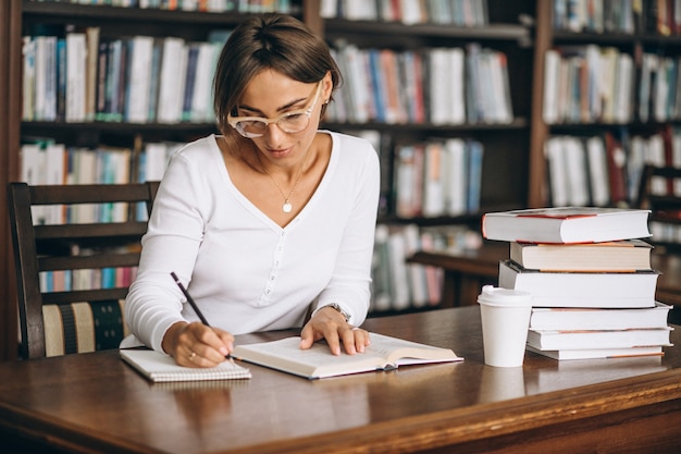 Mujer estudiante estudiando en la biblioteca y tomando café