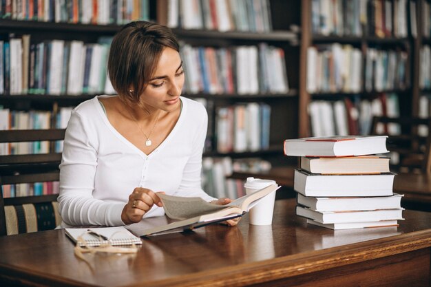 Mujer estudiante estudiando en la biblioteca y tomando café