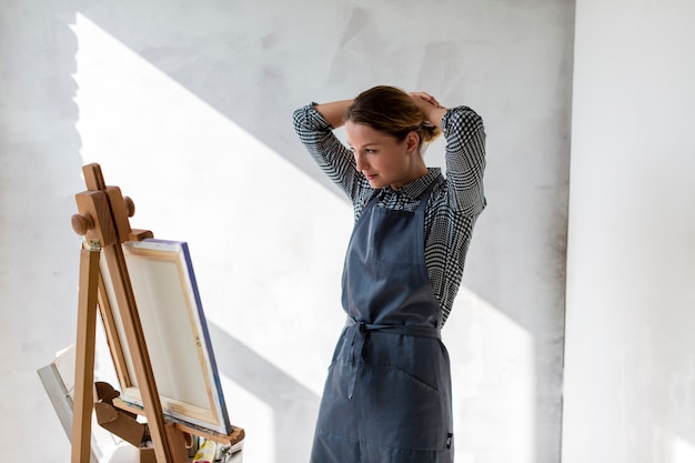 Foto gratuita mujer en estudio con lona y caballete