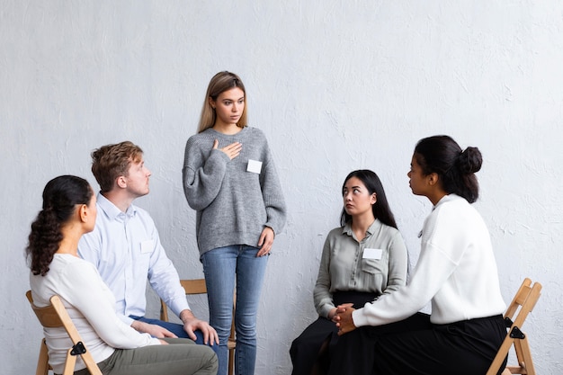 Mujer con etiqueta de nombre hablando en una sesión de terapia de grupo