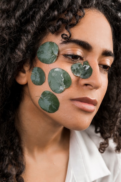 Foto gratuita mujer étnica atractiva con hojas mojadas en la cara