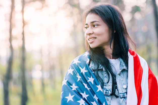 Mujer étnica atractiva posando con la bandera de Estados Unidos.