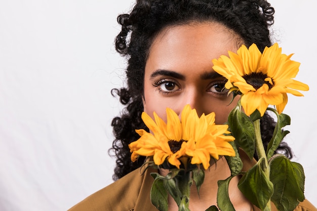 Mujer étnica con flores amarillas cerca de la cara