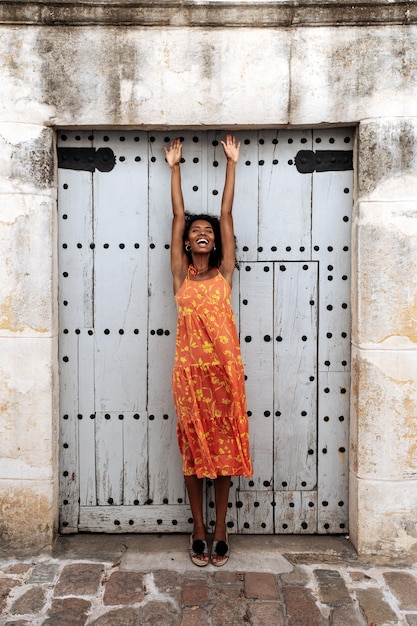 Foto gratuita mujer étnica joven que se coloca cerca de la puerta vieja