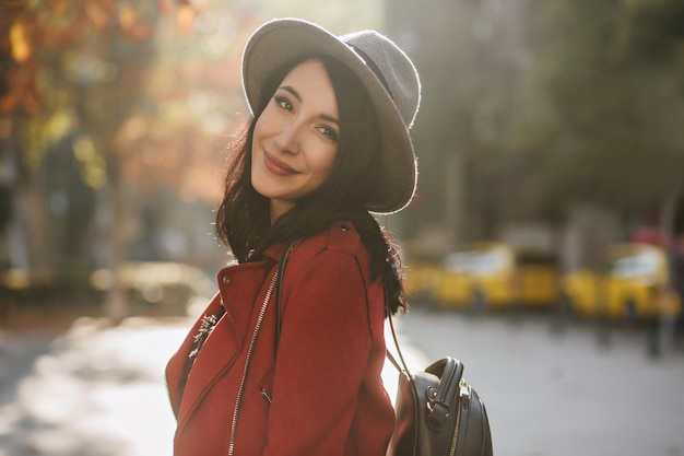 Mujer europea inspirada en chaqueta roja casual mirando a la cámara en la pared de la naturaleza