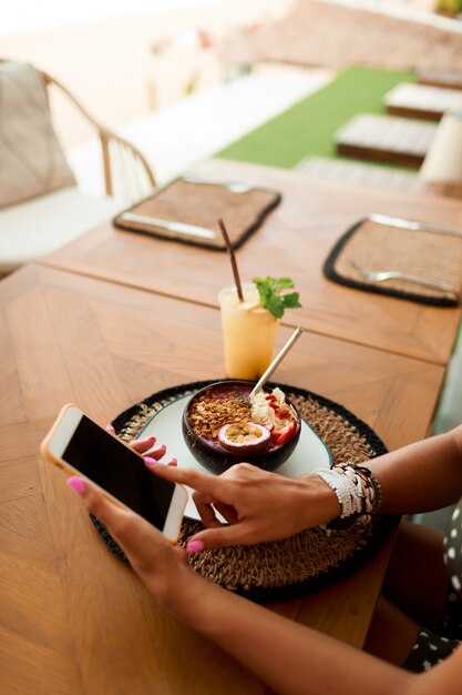 Mujer europea que usa el teléfono móvil en café.