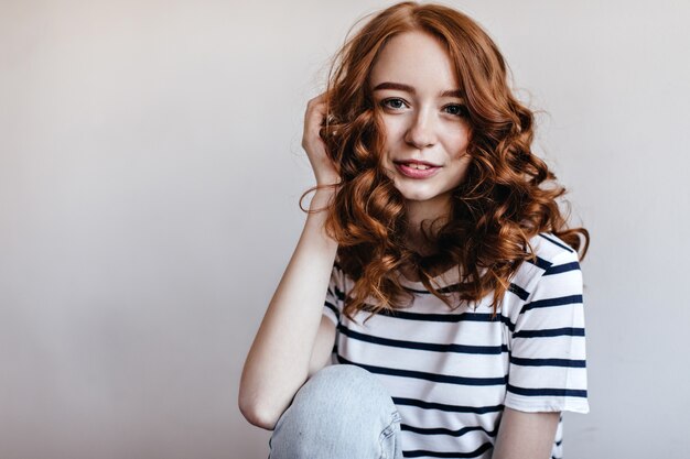 Mujer europea romántica con pelo rojo brillante sonriendo. Foto interior de niña complacida despreocupada expresando felicidad.