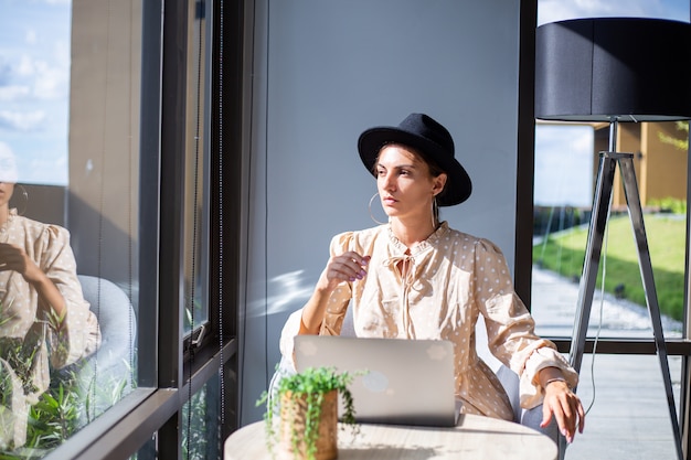 Mujer europea en vestido y sombrero clásico trabaja en casa en la cocina