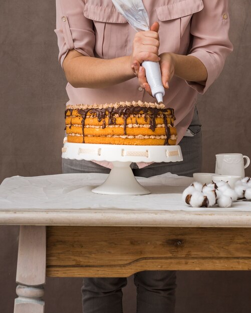 Mujer exprimiendo crema de chocolate sobre pastel