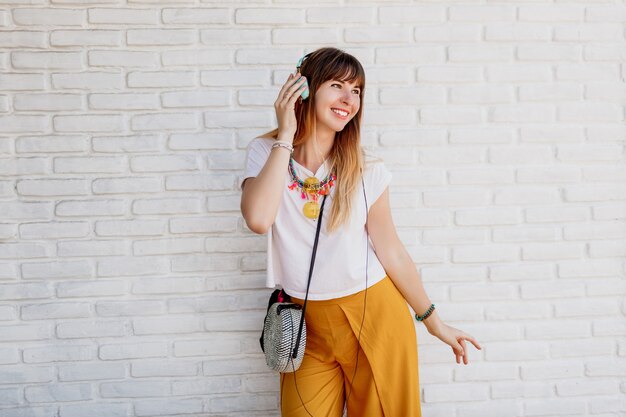 Mujer extática disfrutando de su música favorita con auriculares, bailando y mostrando placer.