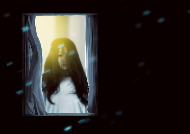 Mujer fantasma aterradora de pie en la ventana. Concepto de halloween