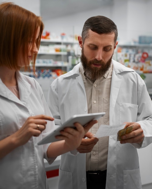 Mujer farmacéutica entrenando a un compañero de trabajo con una tableta en la farmacia