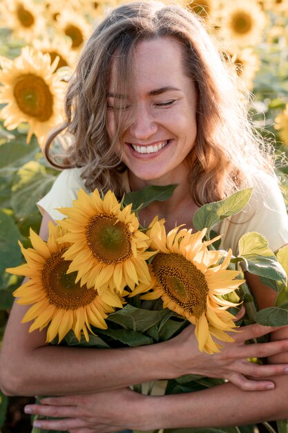 Mujer feliz abrazando girasoles