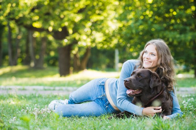 Mujer feliz abrazando a su perro en el jardín