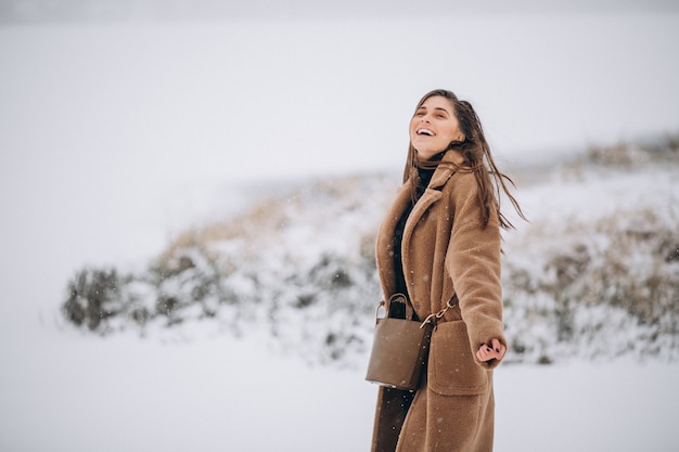 Mujer feliz en abrigo en invierno afuera en el parque