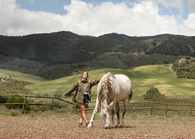 Mujer feliz acariciando a caballo tiro completo