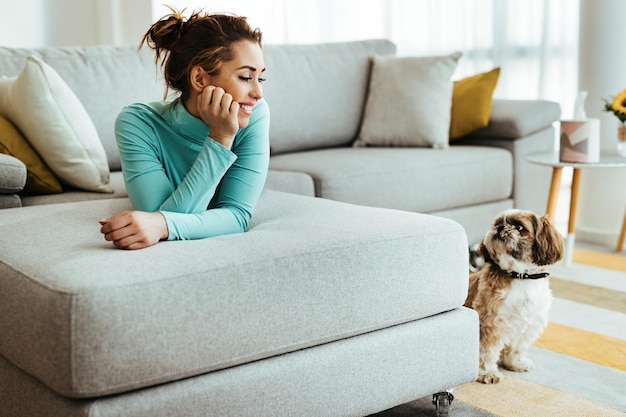 Mujer feliz acostada en el sofá mientras se relaja con su perro en casa