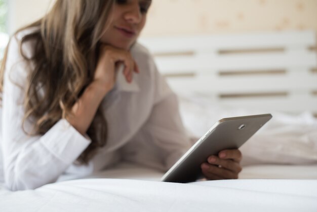 Mujer feliz acostado en la cama con tablet PC