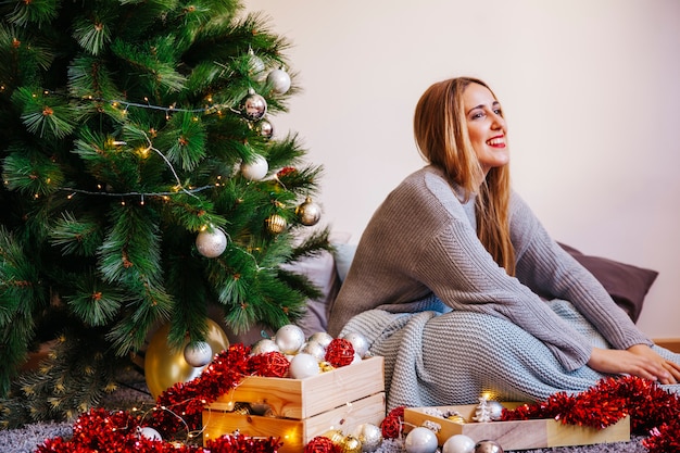 Mujer feliz al lado de su árbol de navidad