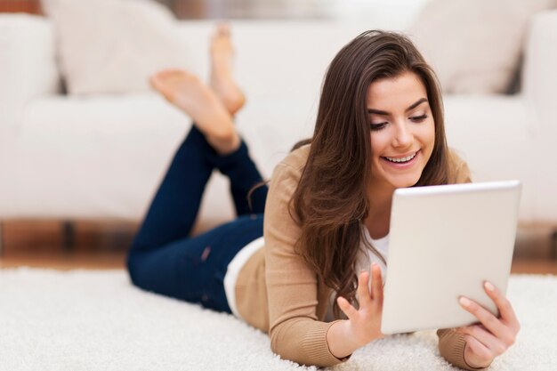 Mujer feliz en la alfombra con tableta digital