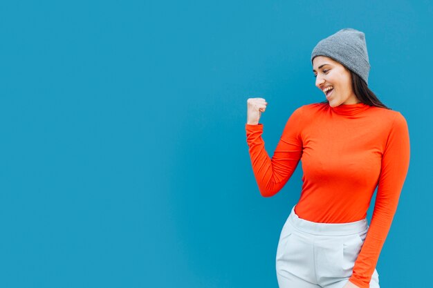 Mujer feliz apretando los puños con sombrero de punto con espacio de copia