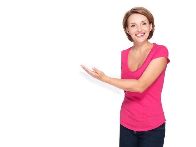 Mujer feliz apuntando con su dedo en banner aislado en pared blanca