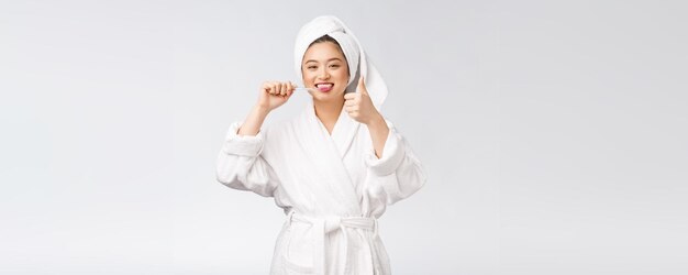 Mujer feliz asiática con cepillo de dientes en albornoz mañana humor
