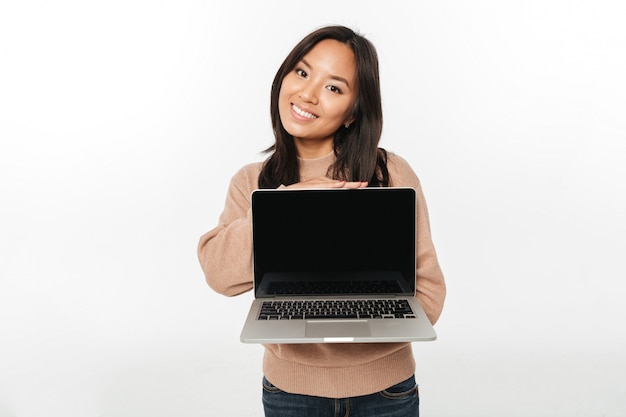 Mujer feliz asiática que muestra la pantalla de la computadora portátil