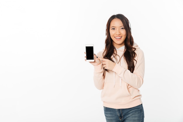 Mujer feliz asiática que muestra la pantalla del teléfono móvil.