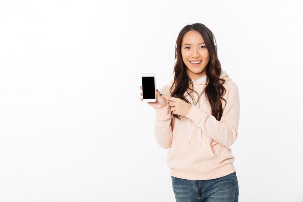 Mujer feliz asiática que muestra la pantalla del teléfono móvil.