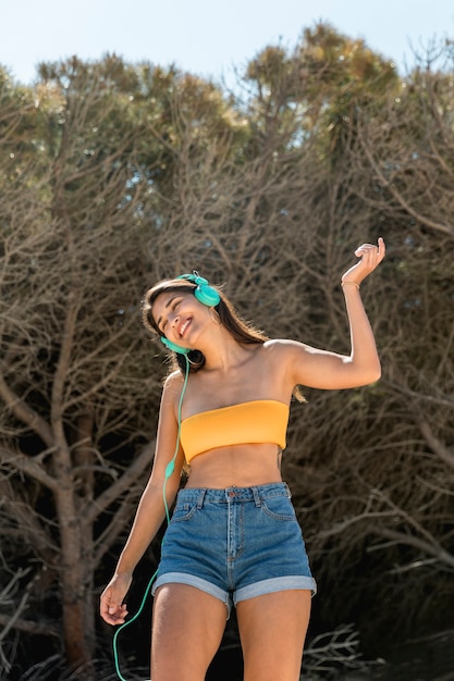 Mujer feliz en auriculares caminando y escuchando música