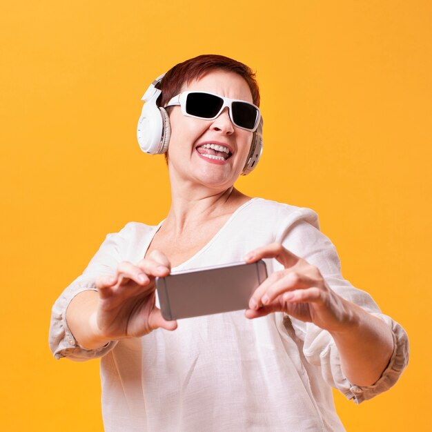 Mujer feliz con auriculares y maqueta de teléfono