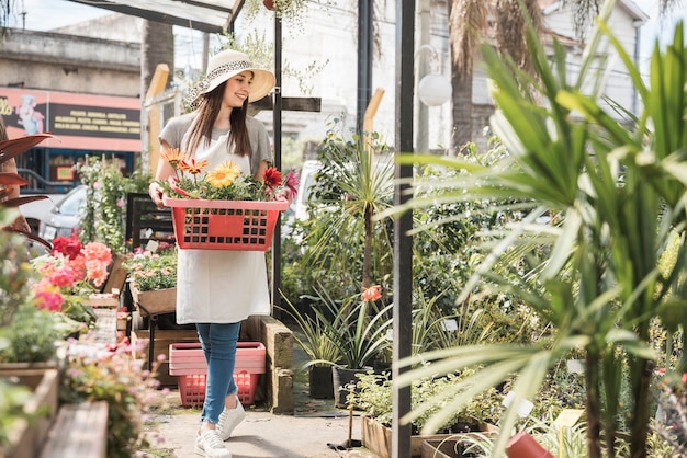 Mujer feliz con la bandeja de flores hermosas que se colocan en invernadero